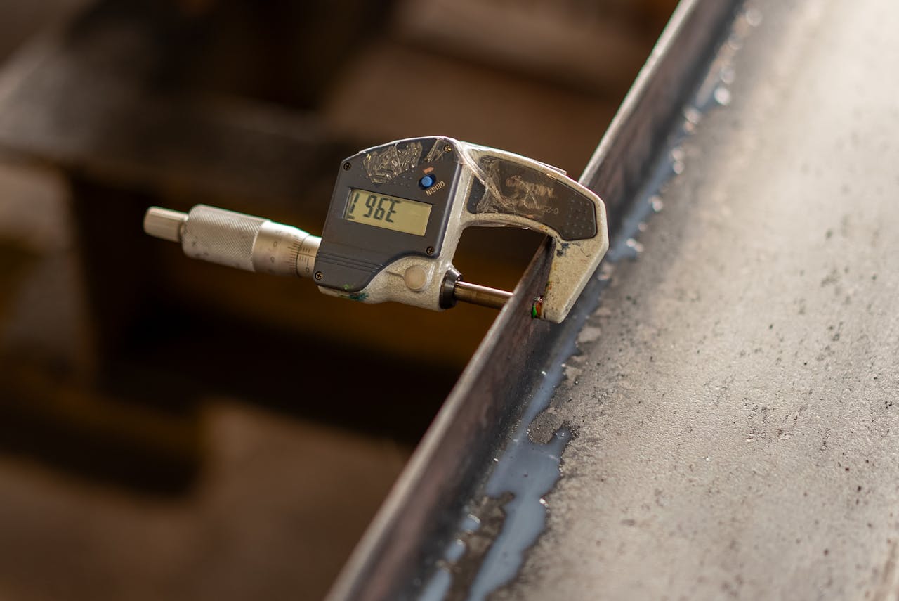 Close-up of digital caliper measuring the thickness of a metal object, showcasing precision engineering.